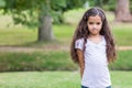 Girl standing in well-kept public park with pink hair clip in hair near tree, copy space Royalty Free Stock Photo