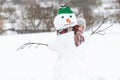 Happy child peeking out behind snowman on winter walk. Winter activities for kids. Kid outside building snow figure