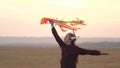 Happy child in a pilot`s helmet runs with a multi-colored kite in his hands at sunset. girl wants to become pilot. child Royalty Free Stock Photo