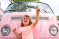 Happy child in pink retro car. Kid hippie. Happy toddler child having fun for travel in pink minivan. Royalty Free Stock Photo