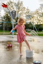 Happy child at playground in public park playing with water. Little girl at splash pad in summer Royalty Free Stock Photo