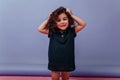 Happy child playing with black curly hair. Studio portrait of little blissful girl enjoying photosho