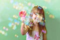 A happy Child is playing with bubbles at home. A photo of a pretty little girl playing with soap bubbles at home. A cute little gi