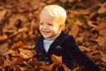 Happy child playing with fallen leaves in autumn park. Little boy have fun playing with fallen golden leaves. Royalty Free Stock Photo