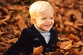 Happy child playing with fallen leaves in autumn park. Little boy have fun playing with fallen golden leaves. Royalty Free Stock Photo