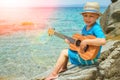 Happy child playing guitar by the sea greece on nature background Royalty Free Stock Photo