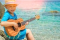 Happy child playing guitar by the sea greece on nature background Royalty Free Stock Photo
