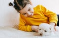 Happy child playing at home with little dogs. Pretty little girl with the puppy. Adorable kid hugging, playing with her pet at the Royalty Free Stock Photo