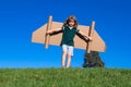 Happy child playing outside on green grass and blue sky. Kid pilot with toy jetpack. Kid boy play with toy plane Royalty Free Stock Photo