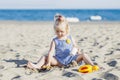 Happy child playing with sand at the beach in summer