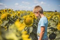 Happy child playing with sunflower outdoor. Kid having fun in green spring field against blue sky background. Healthy and active Royalty Free Stock Photo