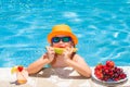 Happy child playing in swimming pool. Summer kids vacation. Summer fruit for children. Little kid boy relaxing in a pool Royalty Free Stock Photo