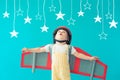 Happy child playing with toy paper wings against blue background Royalty Free Stock Photo