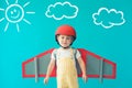 Happy child playing with toy paper wings against blue background Royalty Free Stock Photo