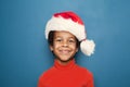 Happy child portrait. Little african american kid boy in Santa hat on blue background Royalty Free Stock Photo