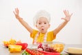 Happy child prepares and eats vegetables in kitchen Royalty Free Stock Photo