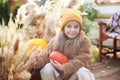 Happy child with pumpkin outdoors in halloween. Smiling girl sit on porch with a pumpkin in her hands. Trick-or-treat. Happy littl