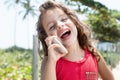 Happy child in a red shirt laughing at mobile phone outside Royalty Free Stock Photo