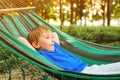 Happy child relaxing in hammock. Summer vacation concept. Cute boy lying in a hammock in garden, dreaming. Happy and healthy Royalty Free Stock Photo