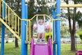 Happy child riding a slide in the playground against the background of purple flowers outdoors Royalty Free Stock Photo