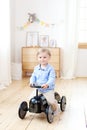 Happy child riding toy vintage car. Funny kid playing at home. Summer vacation and travel concept. Active little boy driving a car Royalty Free Stock Photo