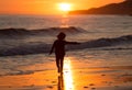 Happy child running on the beach during sunset
