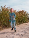 Happy child running jumping having fun on empty autumn beach. Blond girl walking on white sand road