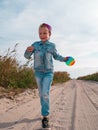Happy child running jumping having fun on empty autumn beach. Blond girl walking on white sand road