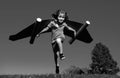 Happy child running with paper wings jumping against blue sky. Portrait of boy playing with toy jetpack. Freedom Royalty Free Stock Photo
