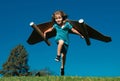 Happy child running with paper wings jumping against blue sky. Portrait of boy playing with toy jetpack. Freedom Royalty Free Stock Photo