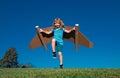 Happy child running with paper wings jumping against blue sky. Portrait of boy playing with toy jetpack. Freedom Royalty Free Stock Photo