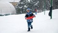 A happy child runs through the snow, sleds in hand, eager to reach the top of the hill for an exhilarating ride down