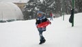 A happy child runs through the snow, sleds in hand, eager to reach the top of the hill for an exhilarating ride down.