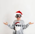 Happy child with Santa Claus face on sweater and red hat. Kid playing pilot and ready to deliver presents. What to Royalty Free Stock Photo