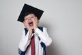 Happy child in a school uniform and the academic hat on white background. Passed exams. Children education