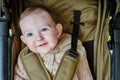 A happy child is sitting in a baby carriage on a studio yellow background. Smiling toddler baby boy in a transformer stroller for