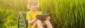 Happy child sitting on the field holding tablet. Boy sitting on the grass on sunny day. Home schooling or playing a Royalty Free Stock Photo