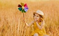 A happy child is sitting in the grass of a summer meadow with a pinwheel