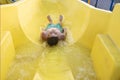 happy child slides down the yellow water slide in the water park. Royalty Free Stock Photo