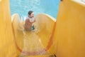 happy child slides down the yellow water slide in the water park. Royalty Free Stock Photo