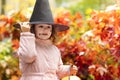 Happy child  with smile in autumn. halloween kids. funny cute girl in black hat with pumpkin Jack, bucket for sweet candy Royalty Free Stock Photo