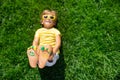 Happy child with smile on feet lying on green spring grass Royalty Free Stock Photo