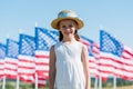 Child standing in dress and straw hat near american flags