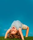 Happy child standing upside down on green grass. Laughing kid boy having fun in spring park. Healthy kids lifestyle Royalty Free Stock Photo