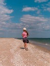 Happy child in a straw hat running jumping having fun on empty autumn sea beach. Blond girl walking on white sand Royalty Free Stock Photo