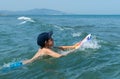 Happy child swim in the sea with a board. Swimming boy on vacation. Kids surfing, joy sport, fun holiday, water splashes Royalty Free Stock Photo