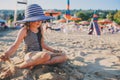 Happy child in swimsuit relaxing on the summer beach and playing with sand. Warm weather, cozy mood.