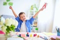 Happy child at the table with school supplies smiles funny and learns the alphabet in a playful way.positive student in a bright