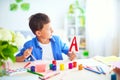 Happy child at the table with school supplies smiles funny and learns the alphabet in a playful way.positive student in a bright