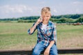 happy child talking by smartphone while sitting on fence and smiling Royalty Free Stock Photo